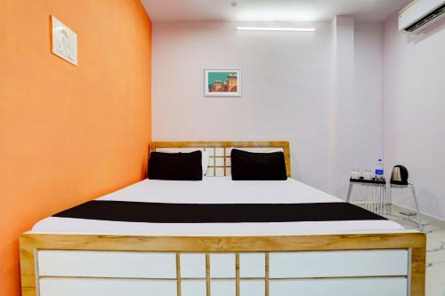 a bed in a room with an orange wall at SPOT ON The SN Lawn in Lucknow