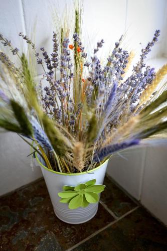 a white vase filled with purple flowers and grass at Glan Llyn Farm House in Mold