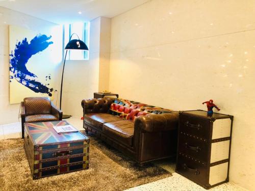 a living room with a brown leather couch and a chair at 알마비즈니스호텔 in Jincheon