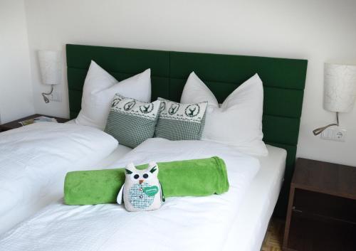 a white bed with green and white pillows and an owl on it at Villa zur Schmied'n in Ehrenhausen