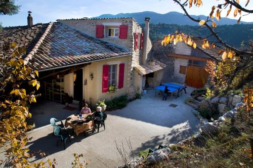 zwei Personen an einem Tisch außerhalb eines Hauses in der Unterkunft La Grange d'Agnès in Montmaur-en-Diois