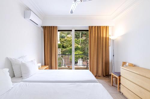 une chambre avec deux lits et un balcon dans l'établissement LE SOLEIA - Spacious 3P - Beachfront - Parking, à Menton