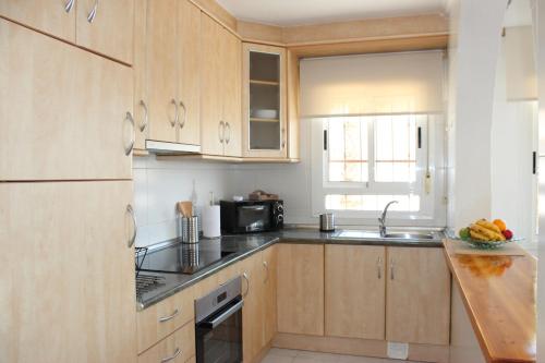 a kitchen with wooden cabinets and a sink and a microwave at Casa Giner in Ciudad Quesada