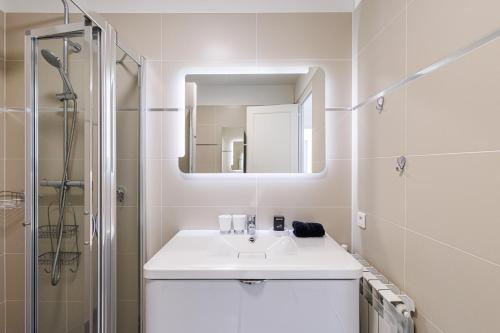 une salle de bain blanche avec un lavabo et une douche dans l'établissement LE SOLEIA - Spacious 3P - Beachfront - Parking, à Menton