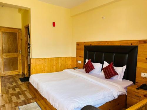 Un dormitorio con una gran cama blanca con almohadas rojas. en Hotel Anchal Residency, en Manali