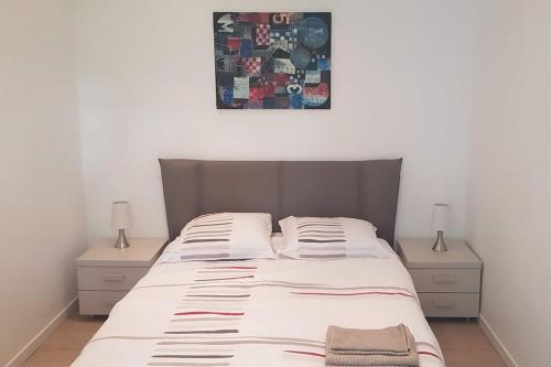 - un lit dans une chambre avec 2 tables de chevet et une photo au-dessus dans l'établissement Appartement 2 pièces cannes, à Cannes