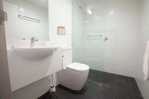 a white bathroom with a sink and a toilet at Little Drifter Canberra in Canberra