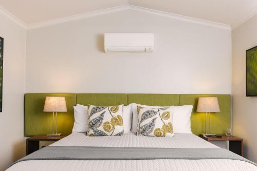 a bedroom with a bed with pillows and two lamps at Spicers Tamarind Retreat in Maleny