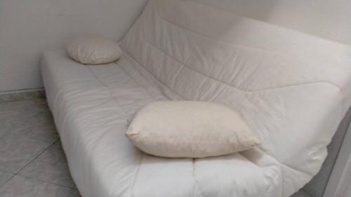 - un canapé blanc avec 2 oreillers dans l'établissement Très Centrale studio mais aux calme!, à Nice