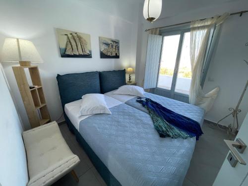 a bedroom with a blue bed with a window at SAND villa in Monolithos