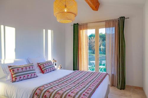 une chambre avec un grand lit et une grande fenêtre dans l'établissement Villa Mas Mavie avec Piscine Les Baux-de-Provence, aux Baux-de-Provence
