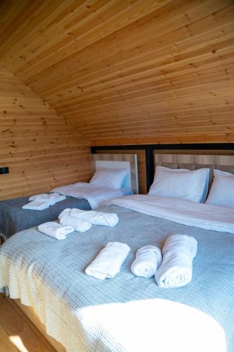 two beds in a wooden room with white pillows at Akhalsheni House in Batumi