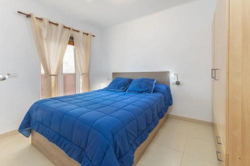una cama azul en una habitación con ventana en APARTAMENTO A 17 M. DE LA PLAYA, en Sant Antoni de Calonge