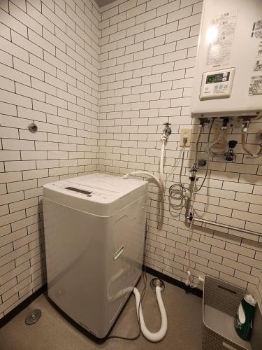 a bathroom with a toilet in a white tiled wall at Snow Nest Lodge in Sapporo