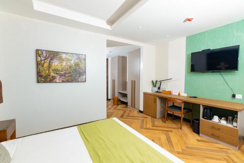 a room with a bed and a desk with a television at Ulwazi Place Hotel by Trianum in Nairobi