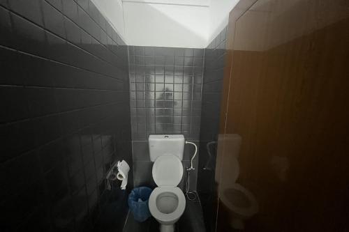 a bathroom with a toilet in a black tiled room at Makotel Hostel Ipoh in Ipoh