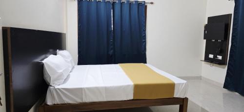 a bedroom with a bed with a blue curtain at RJ Residency Srirangam in Tiruchchirāppalli