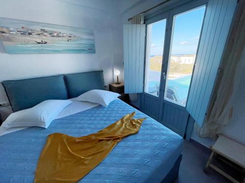 a bedroom with a blue bed and a large window at SEA and SAND villa in Monolithos