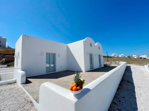 a white house with a bowl of fruit on a porch at SEA and SAND villa in Monolithos