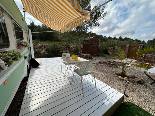 a table and chairs on a wooden deck with an rv at Suite Caravan by Noches de Calig in San Jorge