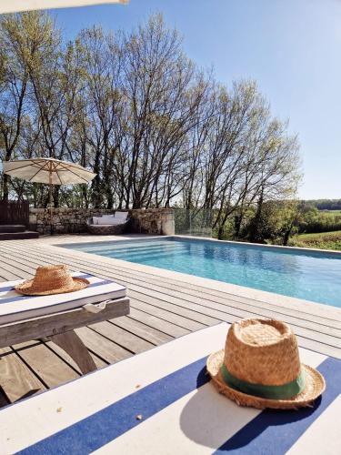 deux chapeaux assis sur une terrasse à côté d'une piscine dans l'établissement Gîte Vin'acacia, à Saint-Romain-la-Virvée