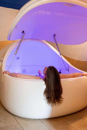 a woman laying in a hot tub in a room at BIO-Hotel Kenners LandLust in Göhrde