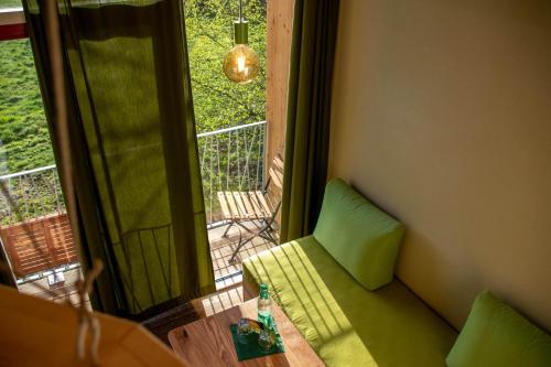 a living room with a green couch and a window at BIO-Hotel Kenners LandLust in Göhrde