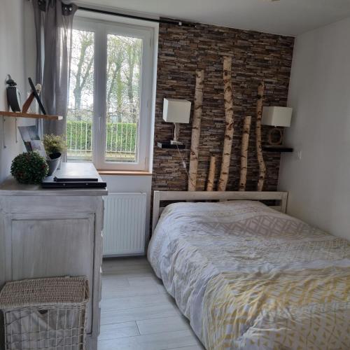 une chambre avec un lit et un mur de briques dans l'établissement Chambre et animaux de la ferme, à Chambord