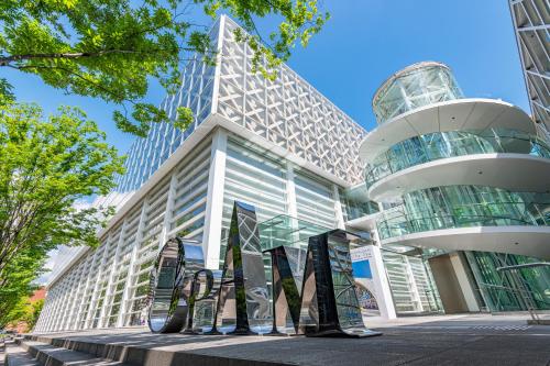 a building with a sculpture in front of it at Tabist Hotel Smart Sleeps Oita Station in Oita