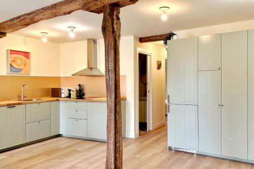 a kitchen with white cabinets and a wooden pole at Parkside Retreats at 1880 House in Bermeo