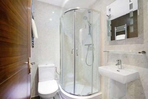 y baño con ducha, aseo y lavamanos. en Queens Park Hotel, en Londres