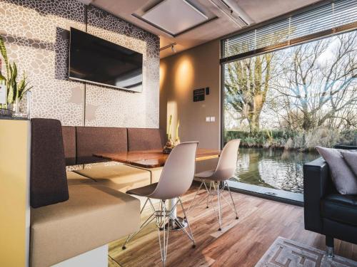 WerkendamにあるAquaHome - NP de Biesbosch - Bijzonder overnachten op een houseboat!のテーブルと椅子と大きな窓のあるダイニングルーム
