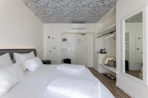 a bedroom with a white bed with a patterned ceiling at Hi Hotels Torbole - Heated Outdoor Pool & Spa in Nago-Torbole