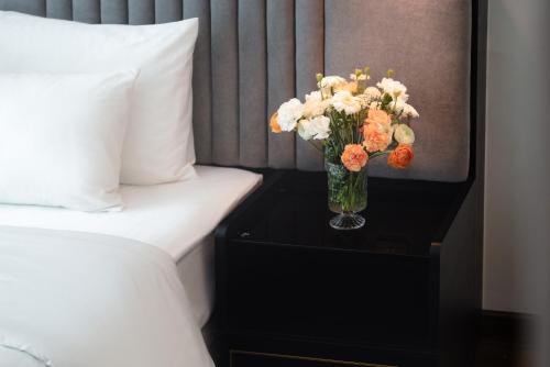 a vase of flowers on a table next to a bed at 22 Land Hotel in Hanoi