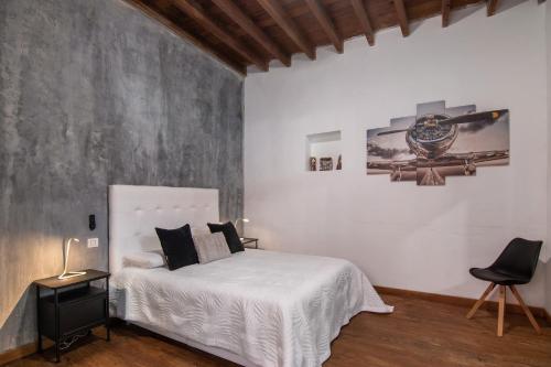 a bedroom with a white bed and a black chair at El Rincon Del Viajero Gran Canaria in Santidad