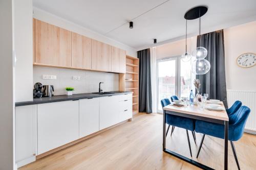 a kitchen with white cabinets and a table with blue chairs at ReVital Mechelinki by Homeprime Parking Free in Mechelinki
