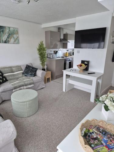 a living room with a couch and a table at Roma's Retreat chalet, Hemsby in Hemsby