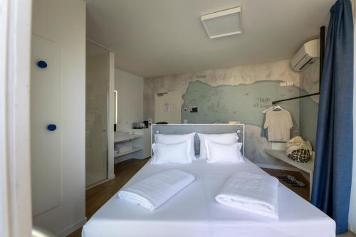 a bedroom with a white bed with white pillows at Hi Hotels Torbole - Heated Outdoor Pool & Spa in Nago-Torbole