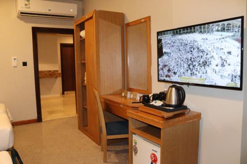 a room with a desk with a large television on a wall at Elaf Ajyad Hotel Makkah in Makkah
