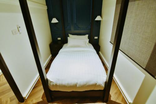 a small bed in a small room with white sheets at เลอค่าเชียงแสน Le Quar Cafe BistroBed & Breakfast in Golden Triangle