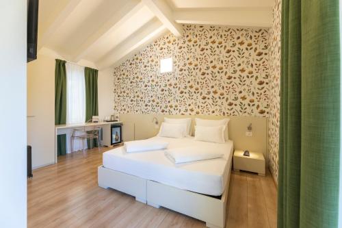 a bedroom with a white bed in a room at Hi Hotels Torbole - Heated Outdoor Pool & Spa in Nago-Torbole