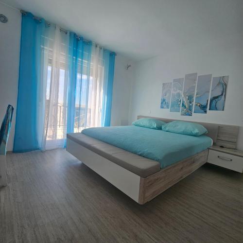 a bedroom with a bed with blue sheets and a window at Villa Hirundinidae in Gornji Muć