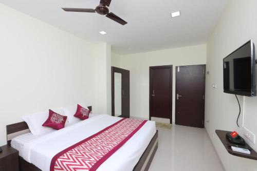 a bedroom with a bed and a flat screen tv at Super Hotel O Perfect Stay Near Meenambakkam Metro Station in Chennai