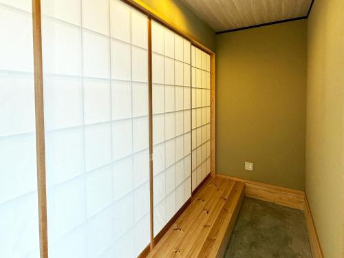 a room with white tile walls and a wooden floor at Nichika House にちか民泊 in Funabashi