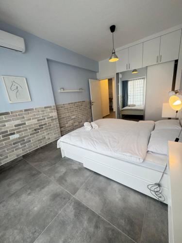 a bedroom with a white bed and a brick wall at Caesar Resort & SPA - Apartment with 2 Bedroom - Aurelius in Saint Yeorgios