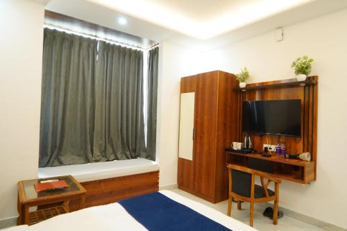 a room with a bed and a tv and a window at MK Regency in Greater Noida