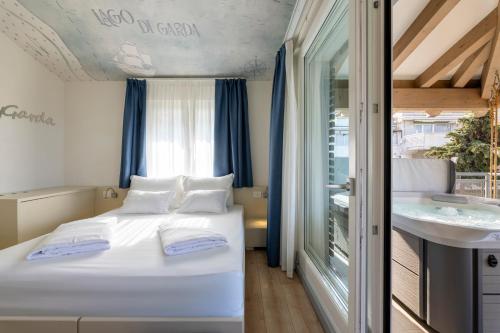 a bedroom with a white bed and a sink at Hi Hotels Torbole - Heated Outdoor Pool & Spa in Nago-Torbole