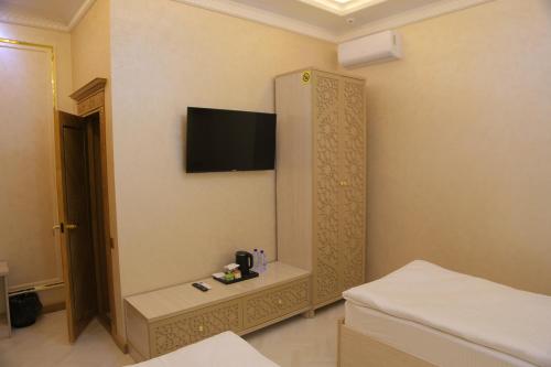 a room with a tv on the wall and a bed at Turon Khiva in Khiva