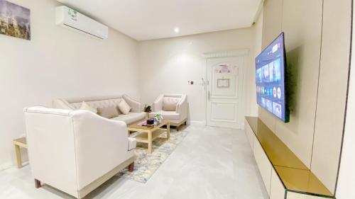 a living room with white furniture and a flat screen tv at Diafat AlSaadah Serviced Apartments- Qurtopa 2 in Riyadh