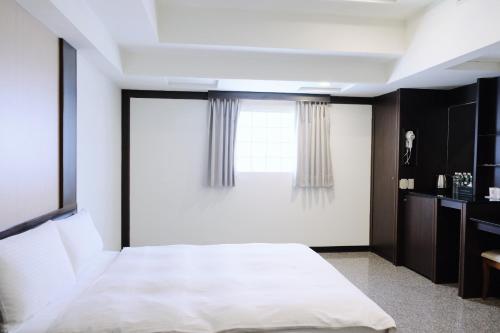 a bedroom with a white bed and a window at YUAI FU HAO Hotel in Taichung